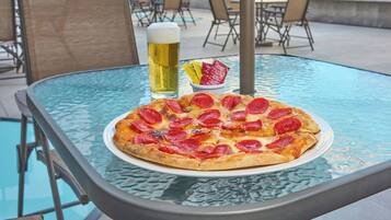 Una mesa de vidrio con una pizza y una cerveza encima.