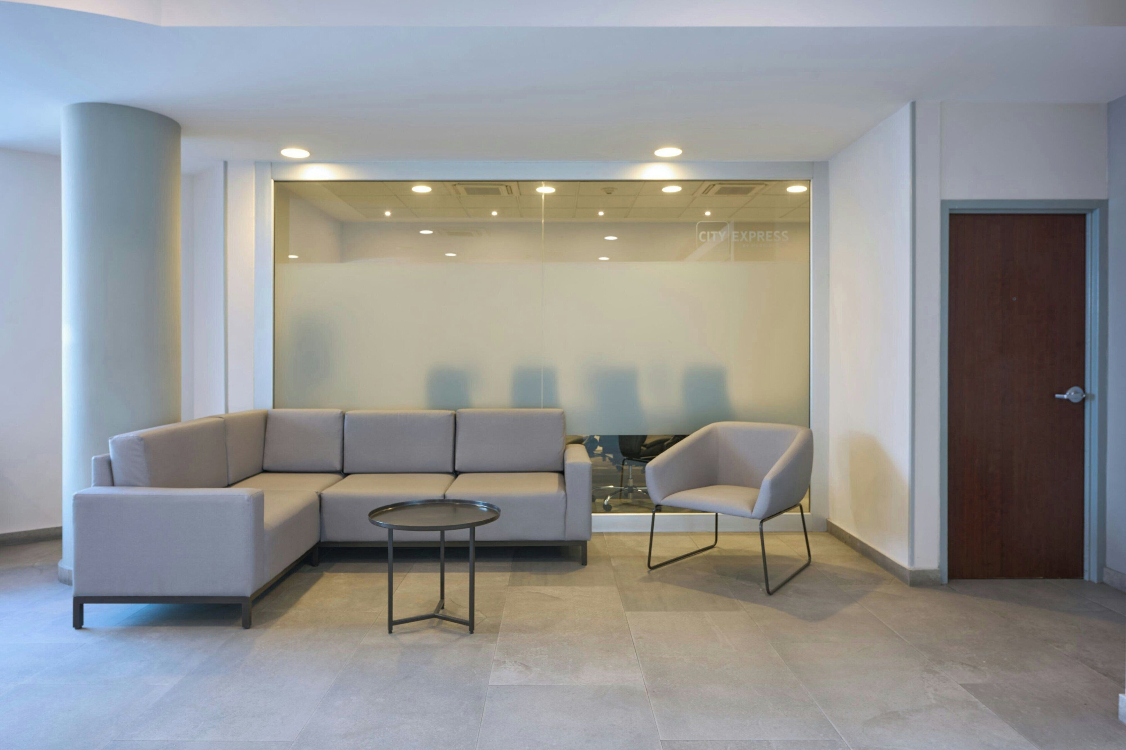 A modern waiting area with a sectional sofa, a small round table, and a single chair.
