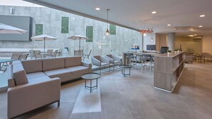 A modern hotel lobby with a large seating area, a bar, and a view of the city. - City Express by Marriott Ciudad de México Aeropuerto (Mexico City)
