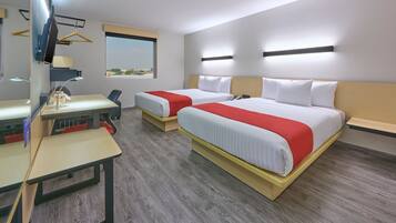 Quarto de hotel com duas camas, uma escrivaninha, uma cadeira, televisão e janela com vista.
