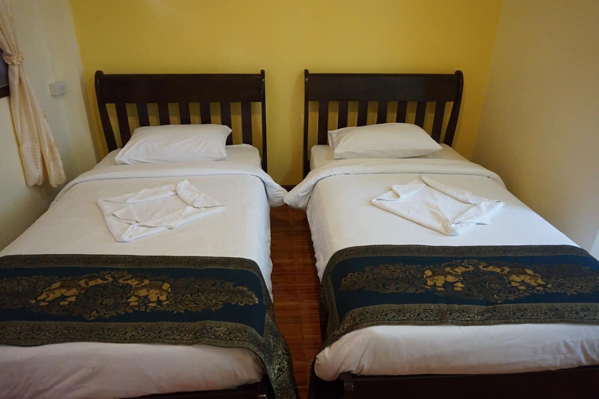 Dos camas individuales con cabeceros de madera, sábanas blancas y colchas bordadas en azul oscuro.