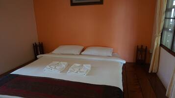 A neatly made bed with white linens and towels, a dark red throw blanket, and a framed picture on the wall.