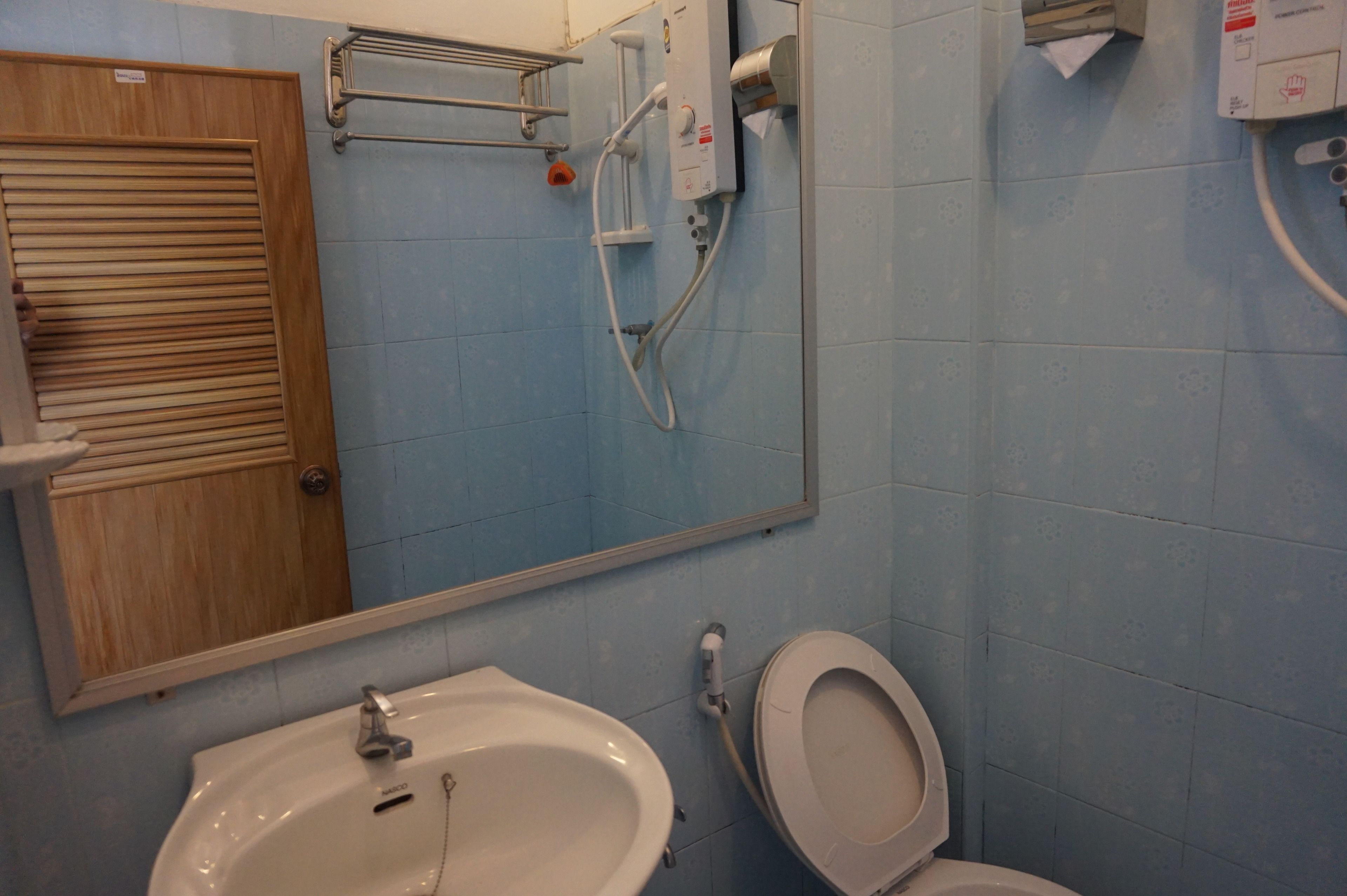 A bathroom with a sink, toilet, and a shower with a control panel.