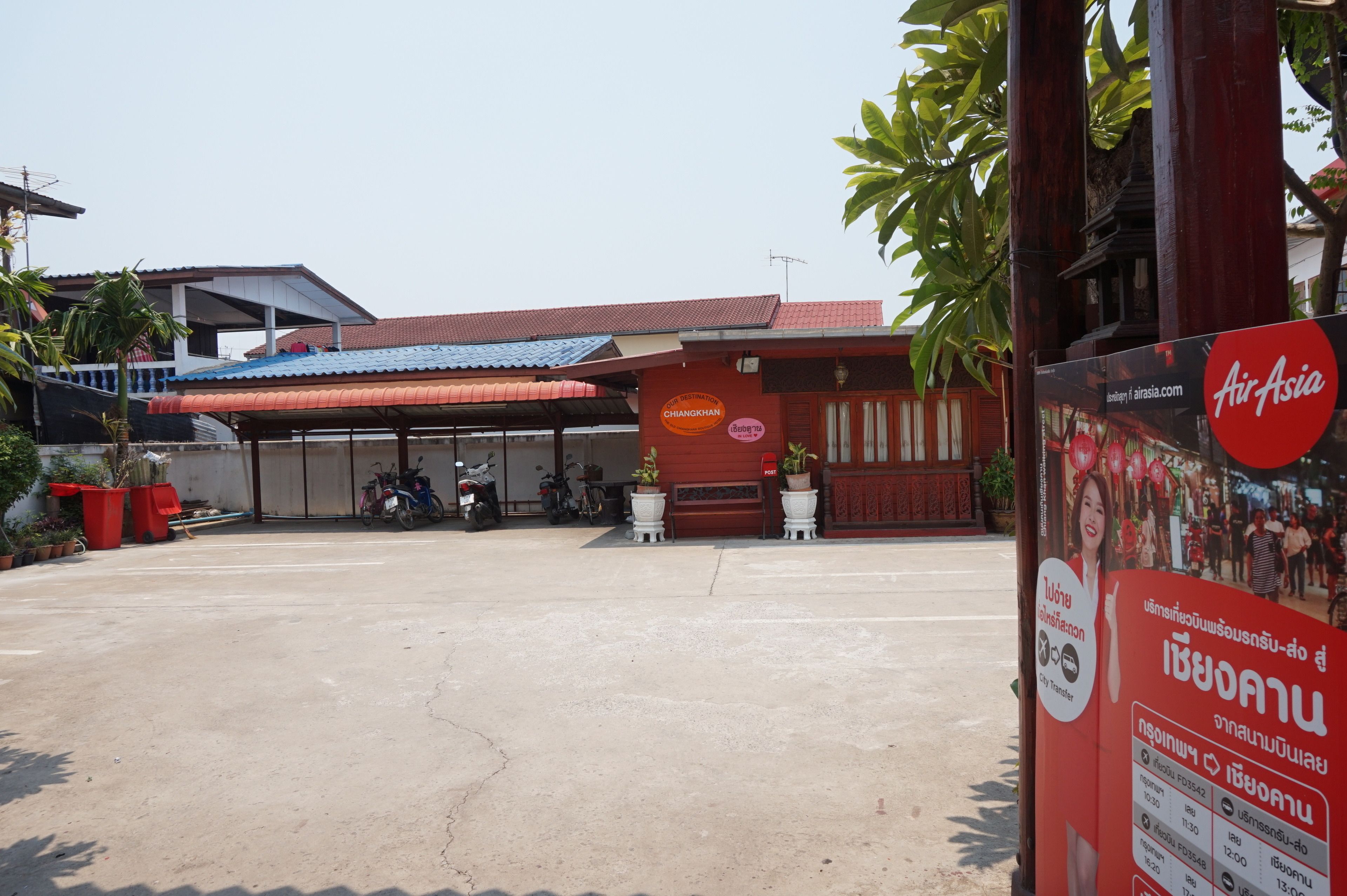 A building with a red roof and a sign for AirAsia. There are potted plants and a motorcycle parked outside.