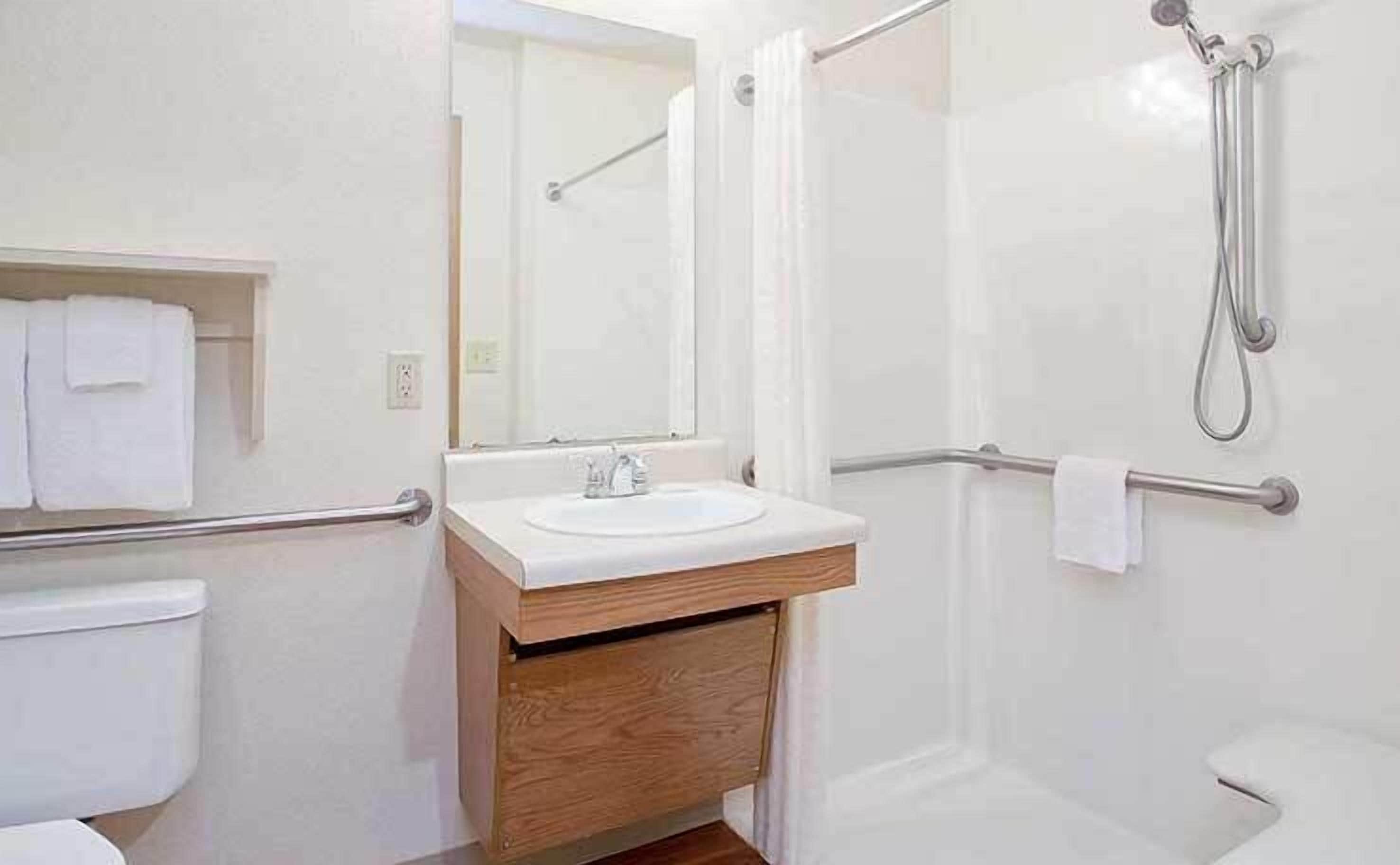A bathroom with a white sink, mirror, and shower area.