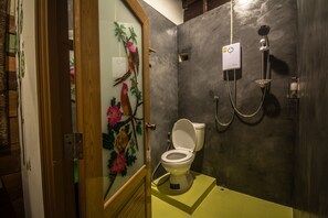 Un baño con inodoro, ducha y una puerta de cristal decorativa.