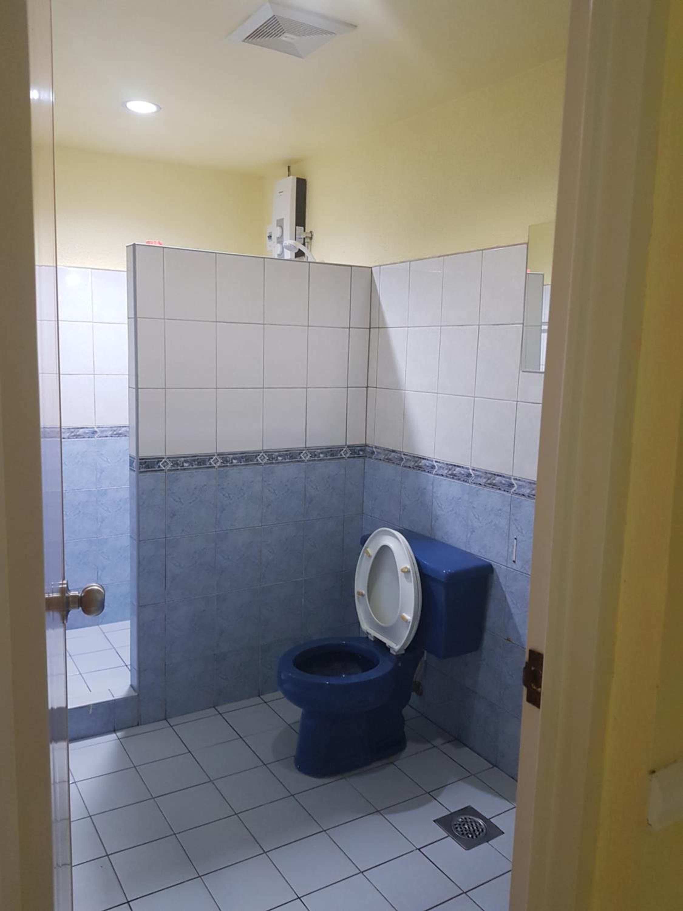 A small bathroom with a toilet, a wall-mounted air conditioner, and tiled walls.