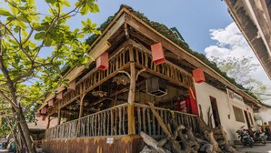 A rustic wooden building with a balcony, a sign for a beer, and a motorcycle parked outside. - HK Beach Resort (Moalboal)