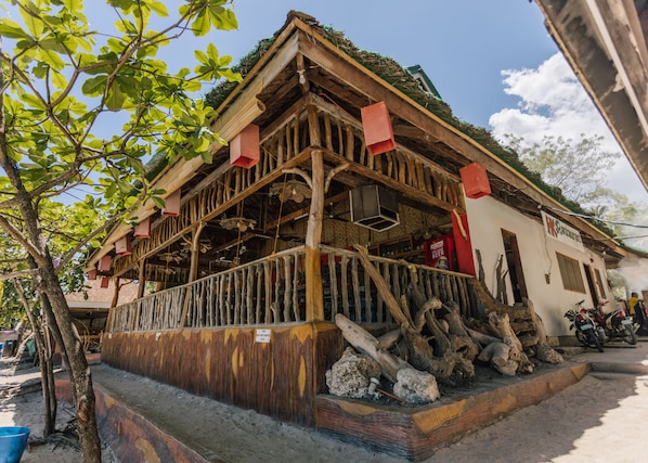 A rustic wooden building with a balcony, a sign for a beer, and a motorcycle parked outside. - HK Beach Resort (Moalboal)