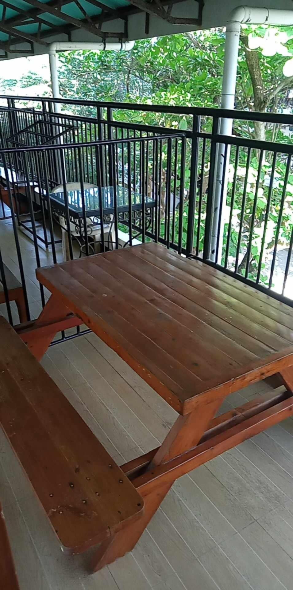 Un banc en bois avec une rambarde en métal, un escalier et une vue sur la verdure.