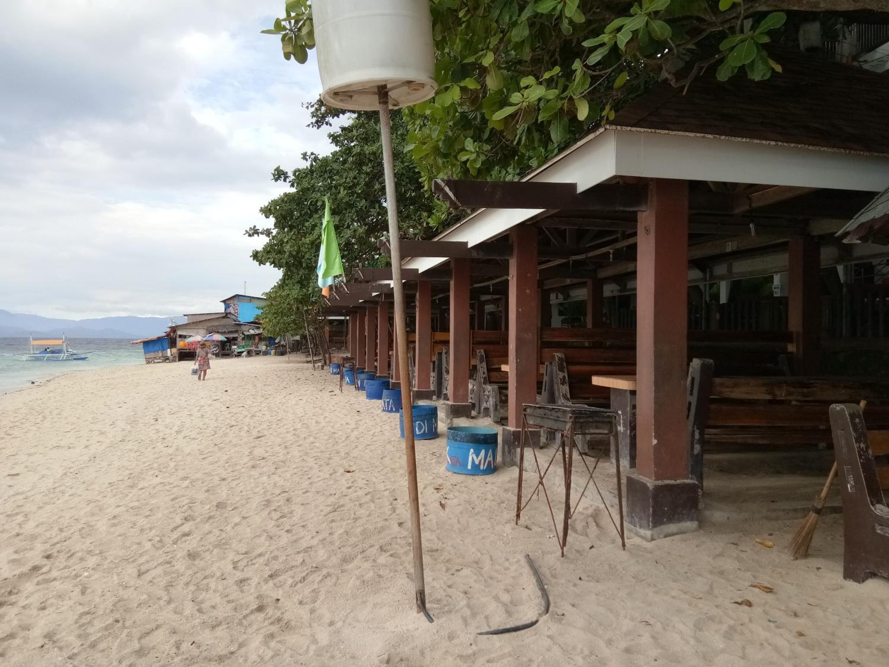Un bâtiment situé au bord de la plage, doté de plusieurs pièces, une plage de sable et un bateau sur l’eau.