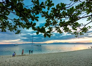 A beach with people, boats, and a clear sky. - HK Beach Resort (Moalboal)