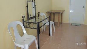 A small room with a glass-top table, two white plastic chairs, a wooden side table, and a white door. - Gorion Beach Resort (Samboan)