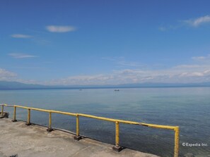 A concrete pier with yellow railings overlooking a calm body of water.