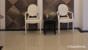 A modern interior with a geometric patterned wall, a chandelier, and two white chairs. - Sun Plaza Subic (Olongapo)