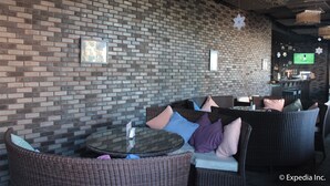 A brick wall with framed pictures, wicker furniture, and hanging lights in a lounge area. - Sun Plaza Subic (Olongapo)