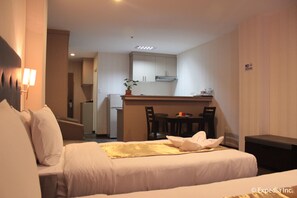 Ein Hotelzimmer mit Bett, einer kleinen Küchenzeile und einem Esstisch.