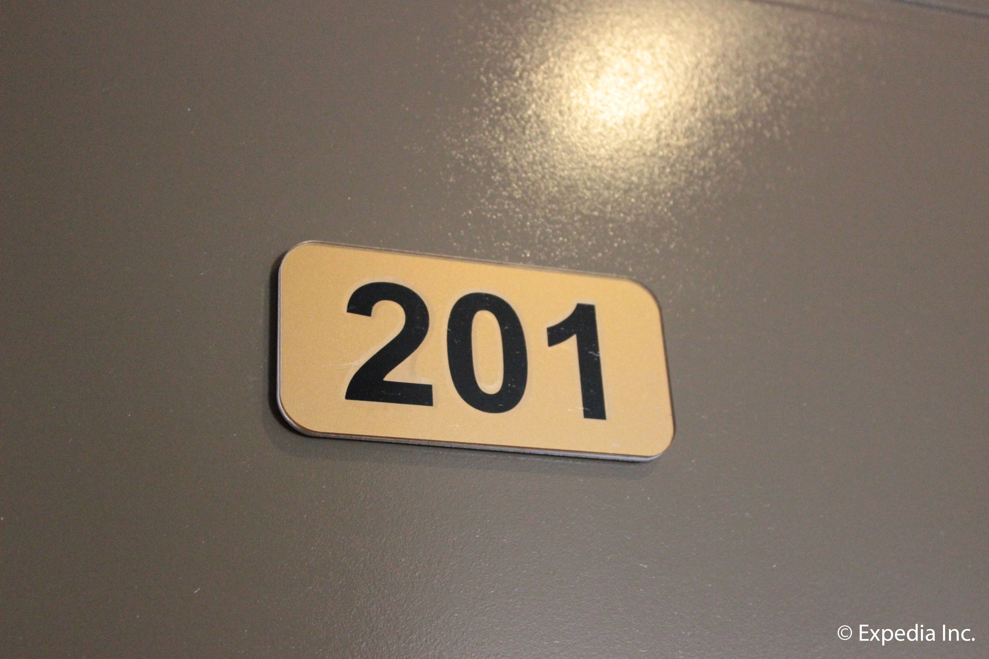 A room number sign with the number 201 on a dark surface.