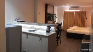 A compact hotel room with a kitchenette, a bed, and a seating area. - Sun Plaza Subic (Olongapo)