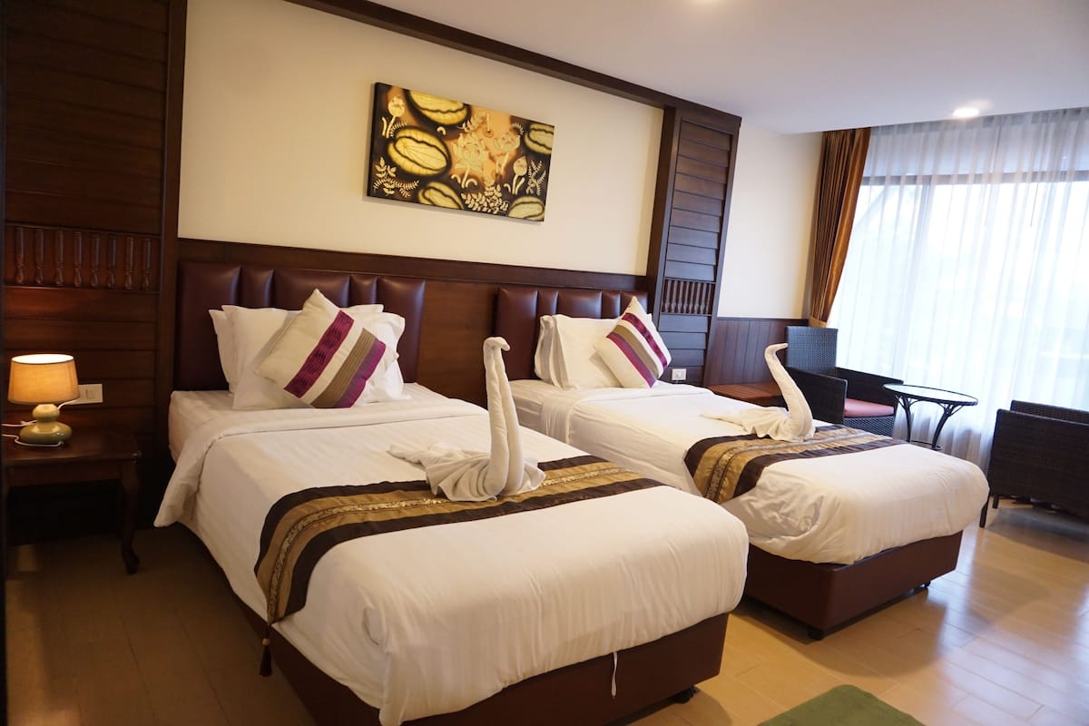 Une chambre d’hôtel avec deux lits, une table de chevet, une table et une chaise.
