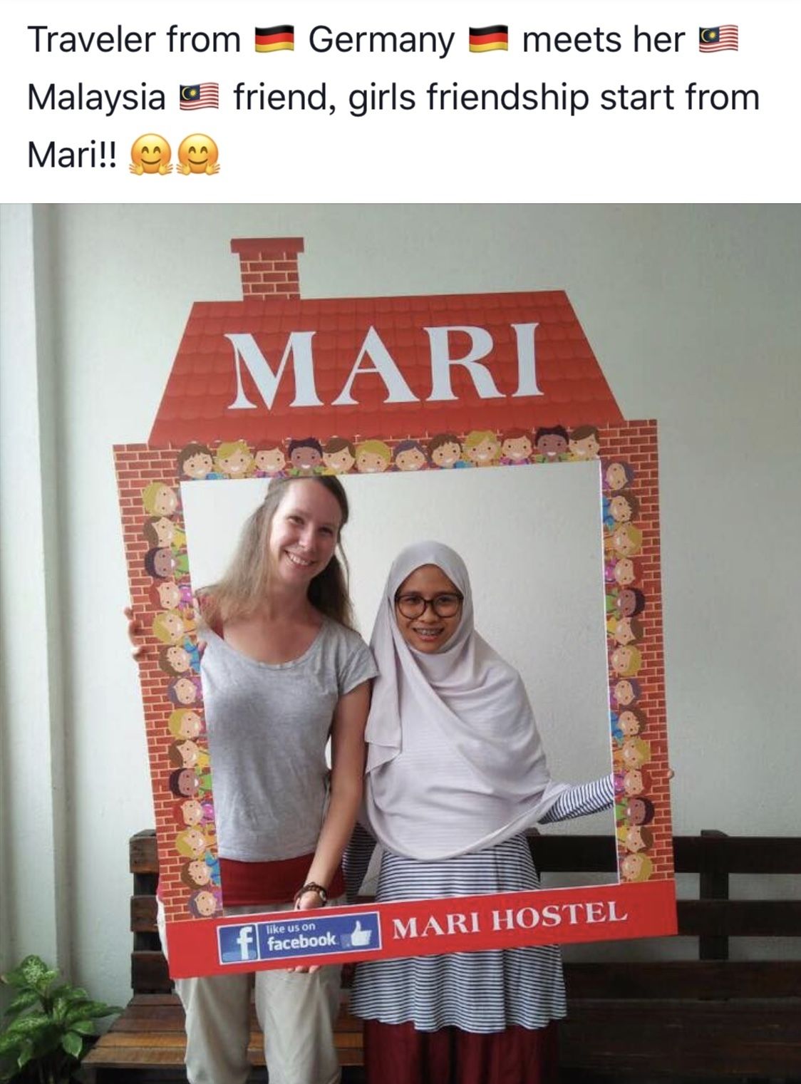 A photo booth with a house-shaped backdrop labeled "MARI HOSTEL" and a Facebook logo.