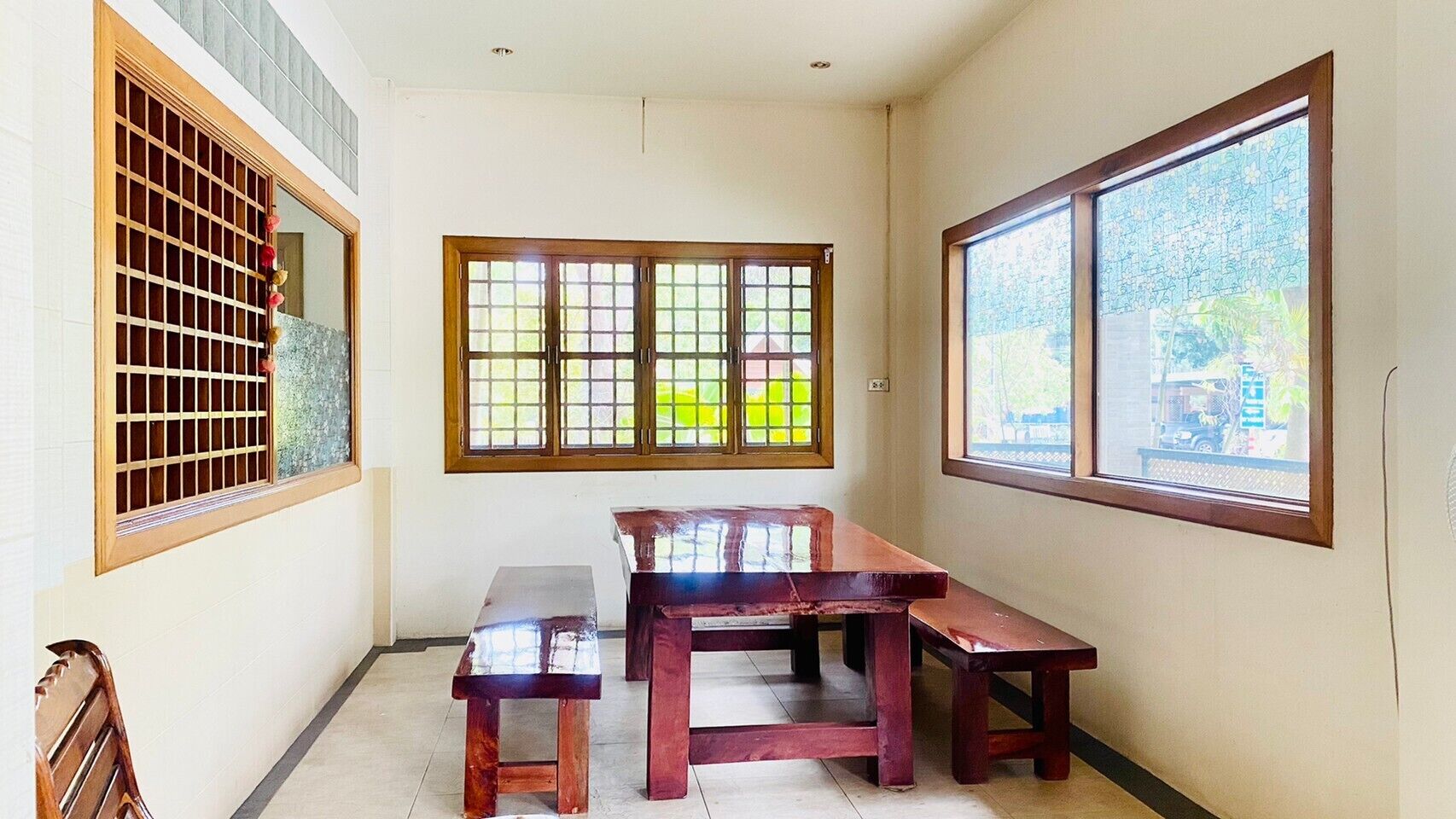 A room with a wooden bench and table, a window with a view, and a traditional wooden door with a grid pattern.