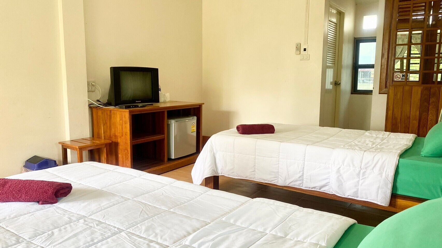 A hotel room with two beds, a television, and a small refrigerator.