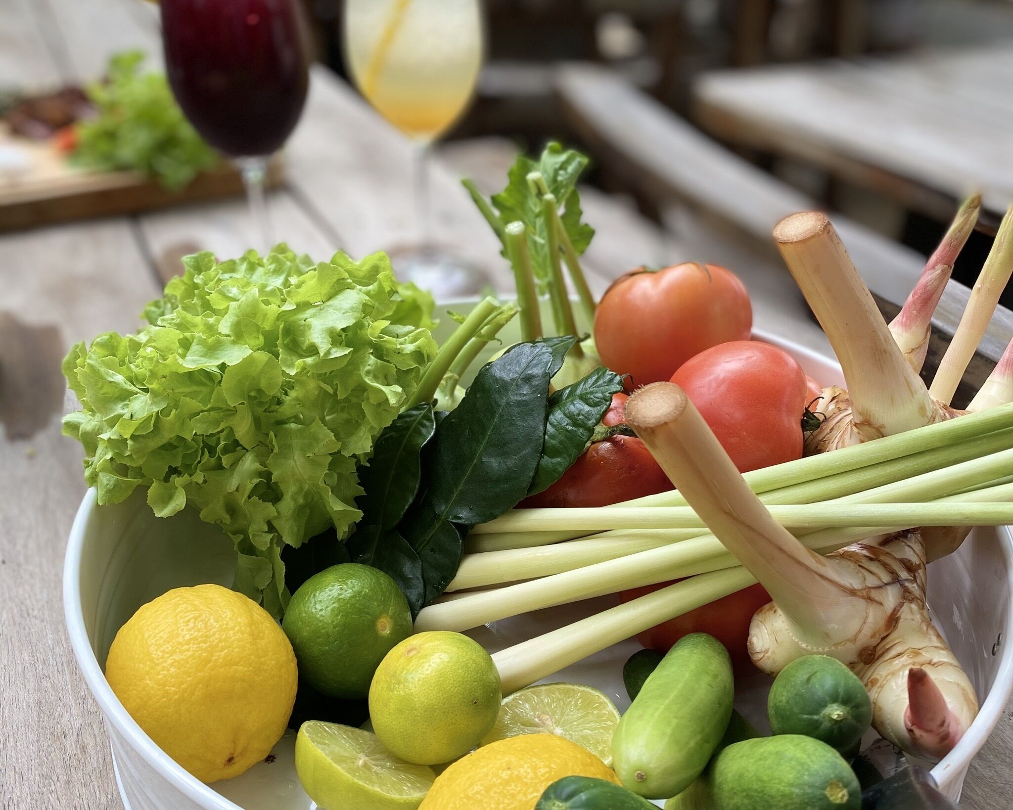 A bowl of fresh vegetables including lettuce, tomatoes, cucumbers, and lemons.