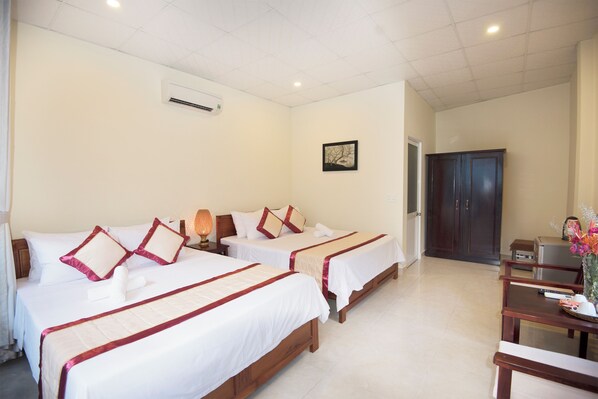 Habitación de hotel con dos camas, un escritorio, una silla, un aire acondicionado y una puerta.
