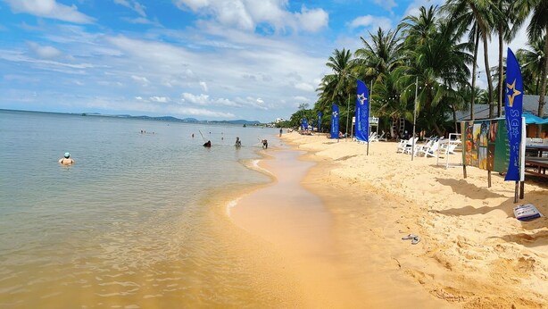 A beach with clear water, palm trees, and beach chairs. - Sunlight Bungalow (Phu Quoc)