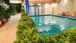 An indoor swimming pool with clear blue water, surrounded by lush green plants. There are lounge chairs along the poolside and a sign for 'Sunlight Bungalow Restaurant'. - Sunlight Bungalow (Phu Quoc)