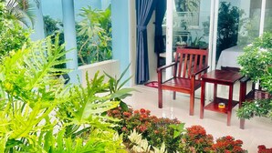 A balcony with a wooden chair and table, surrounded by various plants and flowers. - Sunlight Bungalow (Phu Quoc)