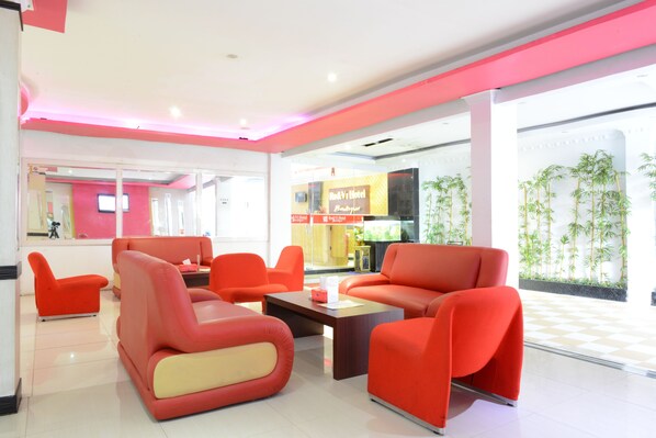 A modern lobby with red seating, a reception desk, and a digital screen.