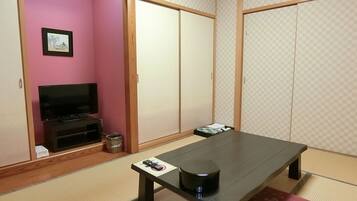 A room with a television, a tatami mat, a low table, and sliding doors.