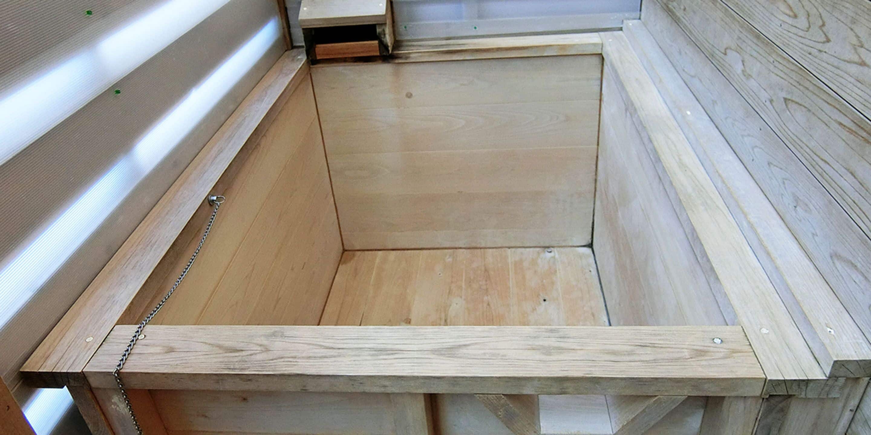 Estructura de cama de madera con cadenas metálicas y cabecera de madera.