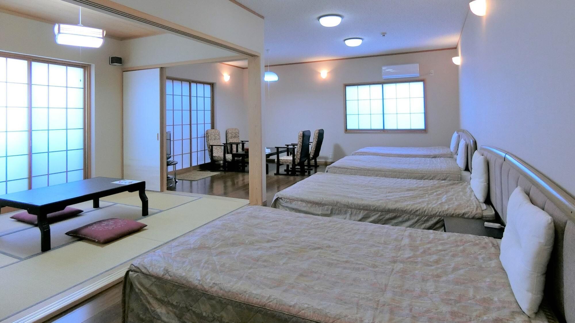 A hotel room with three beds, a small table, chairs, and a sliding door leading to a dining area.