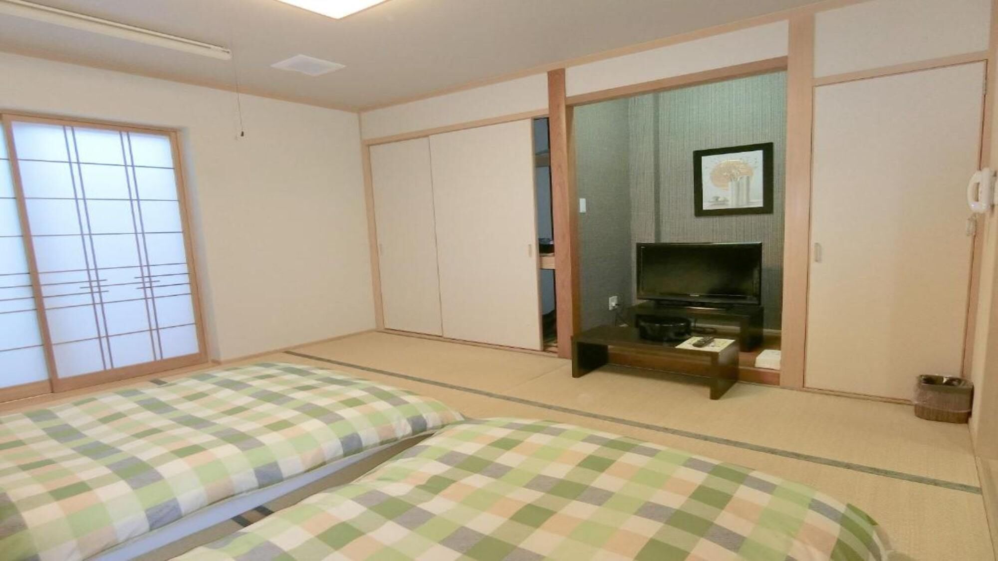 A room with tatami flooring, a television, and a sliding door.