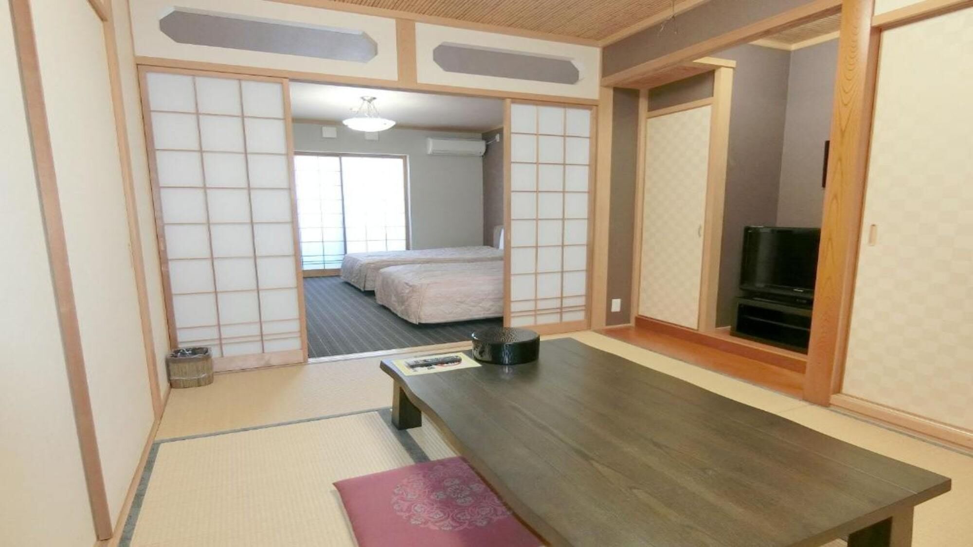 A traditional Japanese-style room with tatami flooring, a low table, and sliding doors.