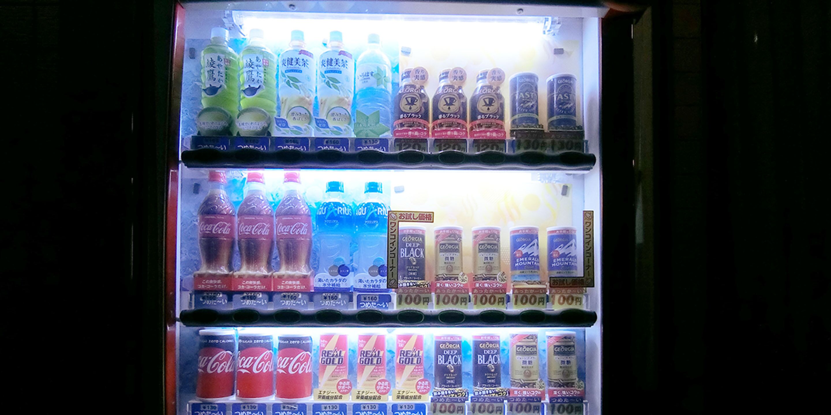 Un distributeur automatique proposant une variété de boissons, notamment du Coca-Cola et d’autres boissons.