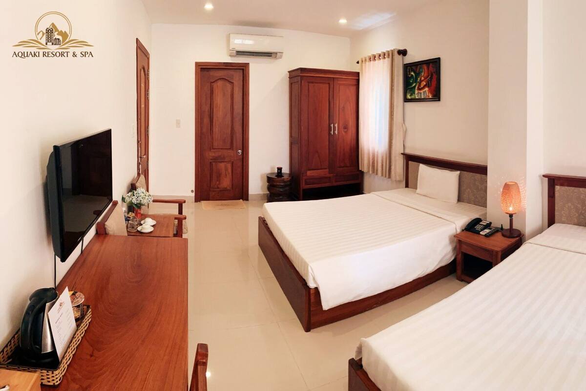 A hotel room with two beds, a TV, a desk, and a wardrobe.