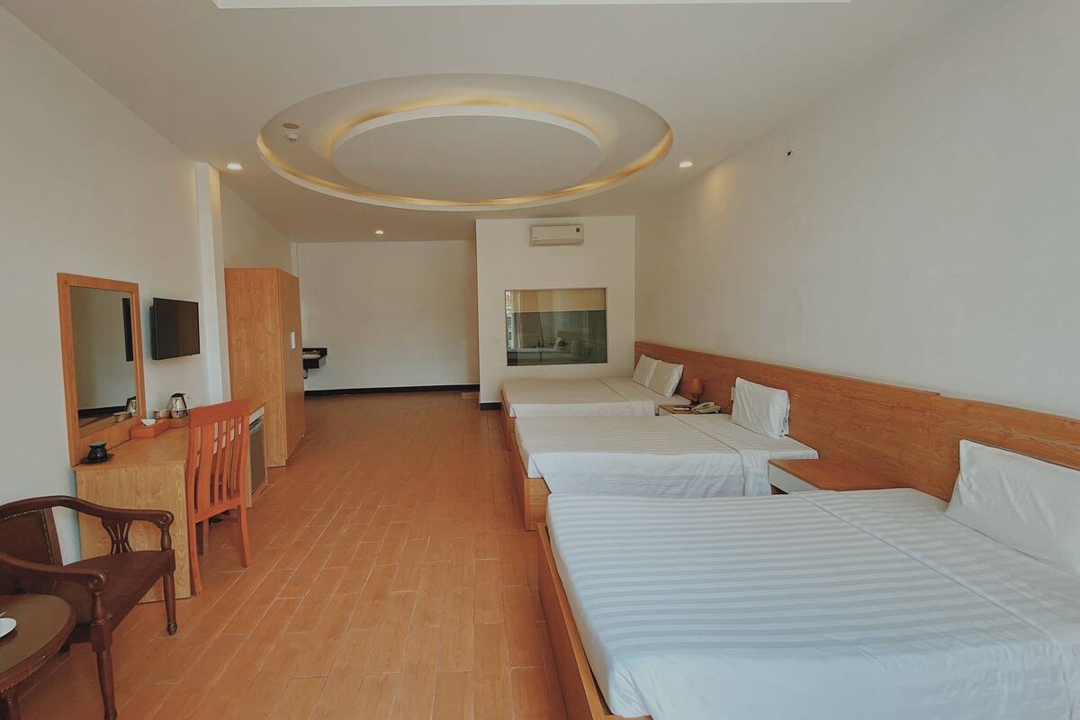 A hotel room with two beds, a wooden desk, a mirror, and a television.