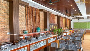 Ein reichhaltiges Buffet mit mehreren Servicestationen, einer Auswahl an Speisen und einem Sitzbereich mit Tischen und Stühlen.