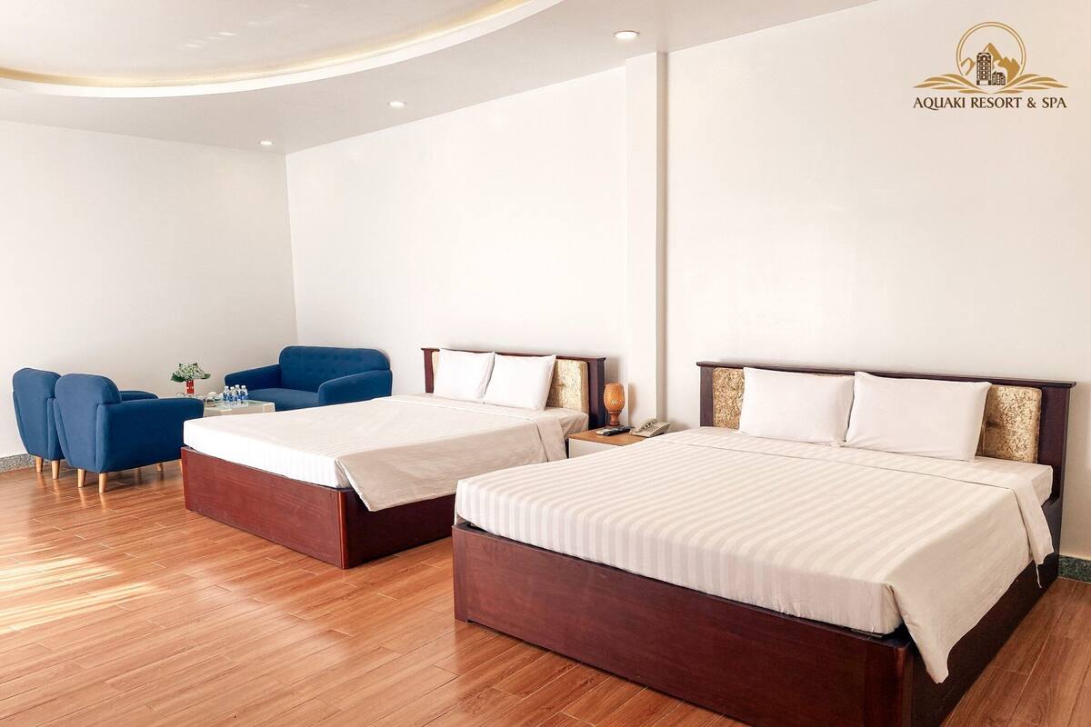A hotel room with two beds, a desk, and a chair.