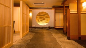 A hallway with wooden paneling, a stone floor, and a circular wall feature with a textured pattern. - Hotel ISAGO Kobe (Kobe)