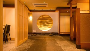 A hallway with a stone floor, wooden paneling, and a circular wall decoration. - Hotel ISAGO Kobe (Kobe)