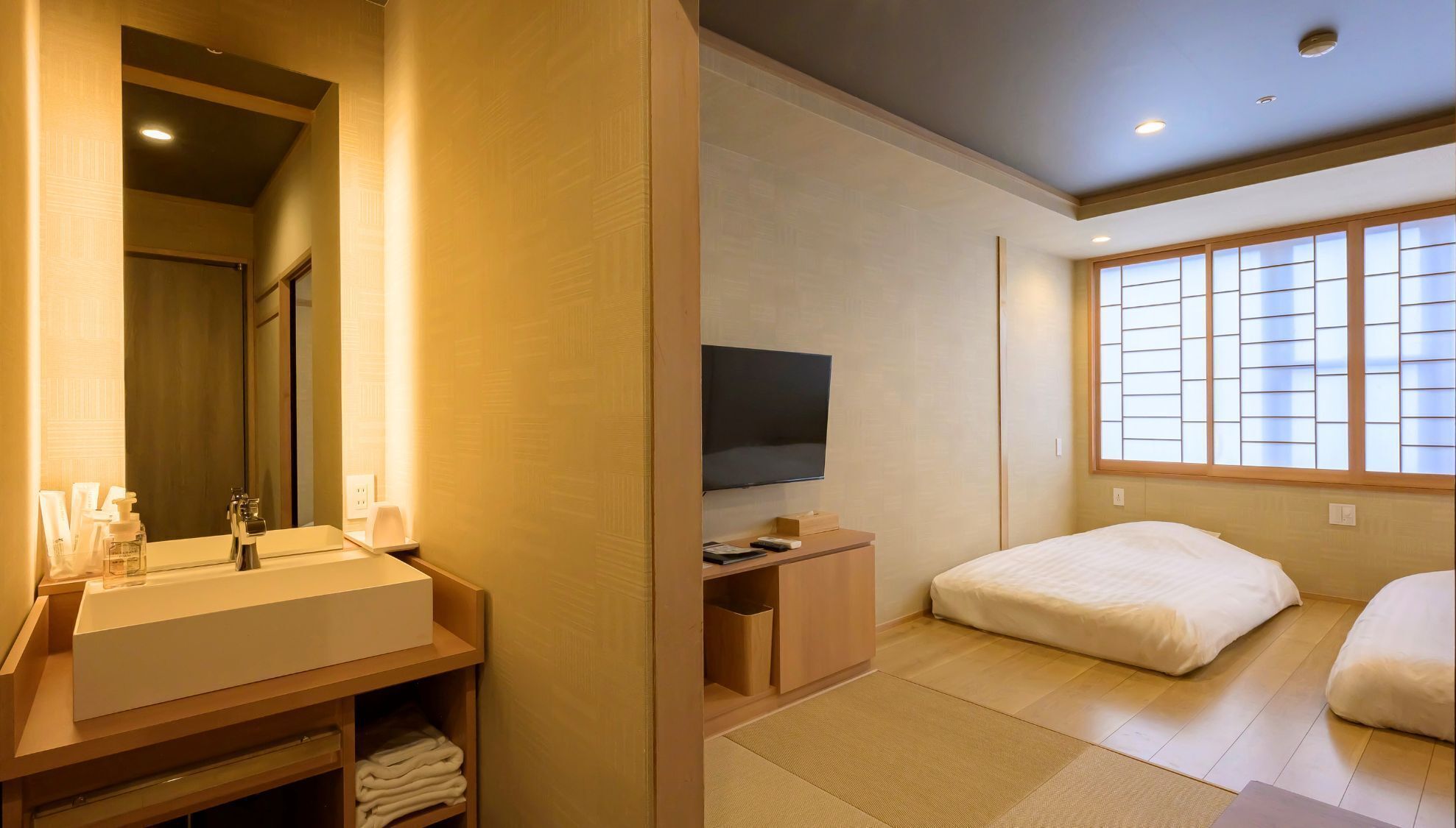 Ein Hotelzimmer mit einem Holznähegang, einem Flachbildfernseher, einem Bett und einem Fenster mit Shoji-Bildschirmen.