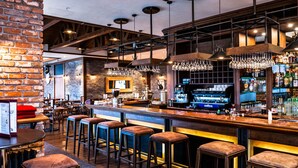 A bar area with stools, a counter, and hanging light fixtures.