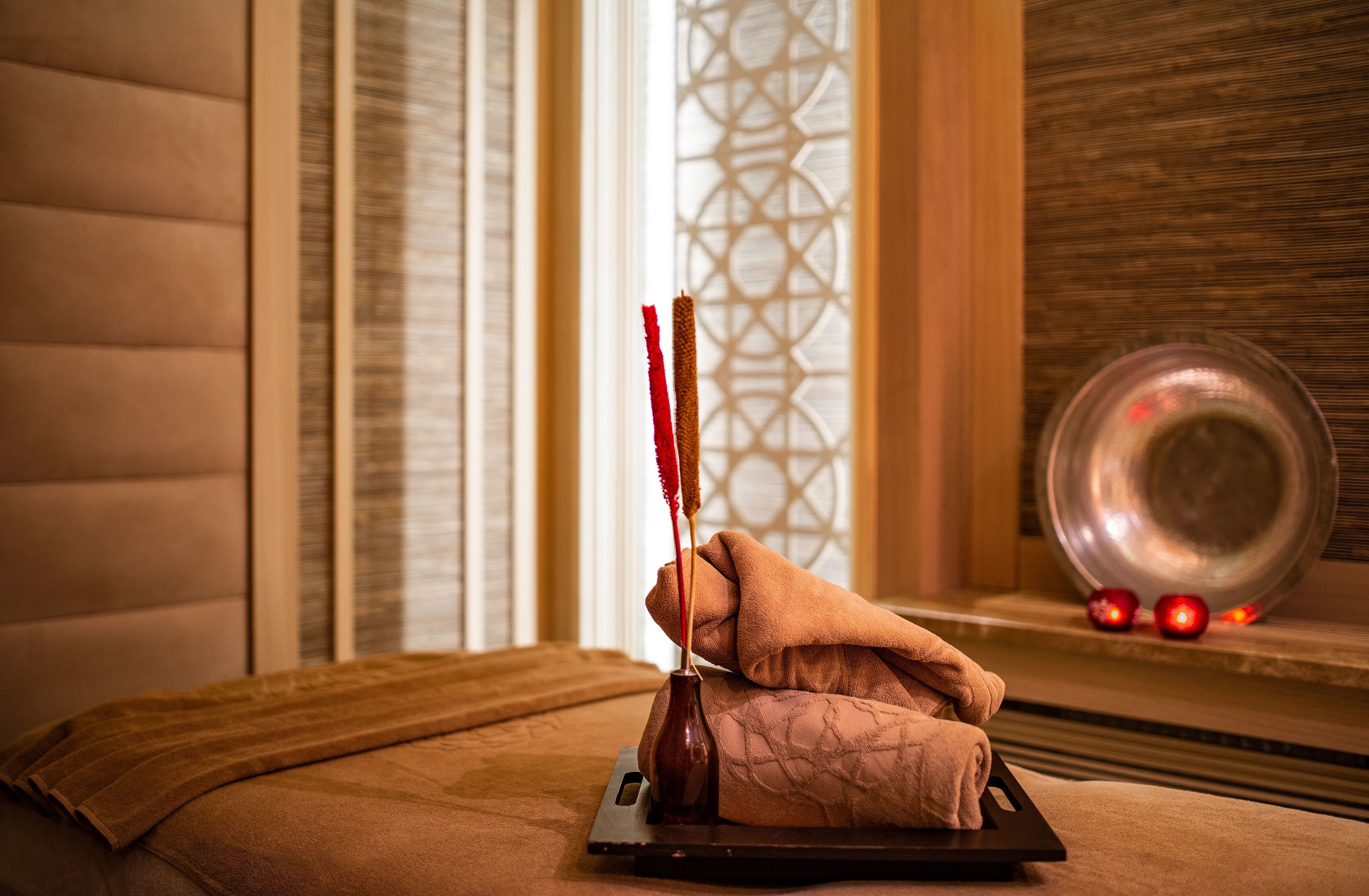 A massage table with a towel, a small bottle, and a decorative plate with red ornaments.