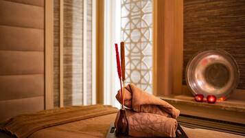 A massage table with a towel, a small bottle, and a decorative plate with red ornaments.