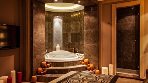 A modern bathroom with a freestanding bathtub, a shower, and a flat-screen TV mounted on the wall.